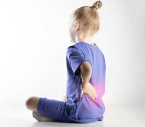 Imagen de una niña con evidente malestar en la zona lumbar, simbolizando los síntomas que pueden indicar espondilodiscitis infecciosa en pacientes pediátricos.